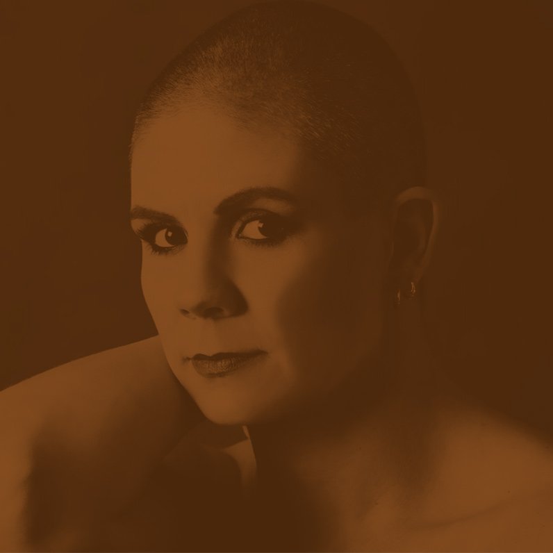 A woman with shaved head is looking at the camera.